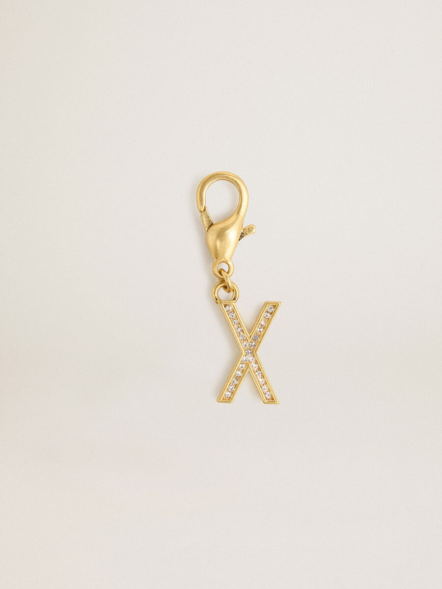 bedeltje met de letter x in goudkleurig messing met kristallen.