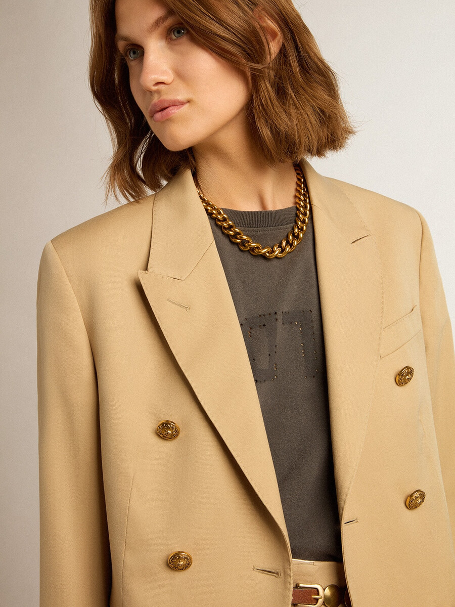 damesblazer met dubbele rij knopen in zandkleur met gouden knopen in heraldisch motief.
