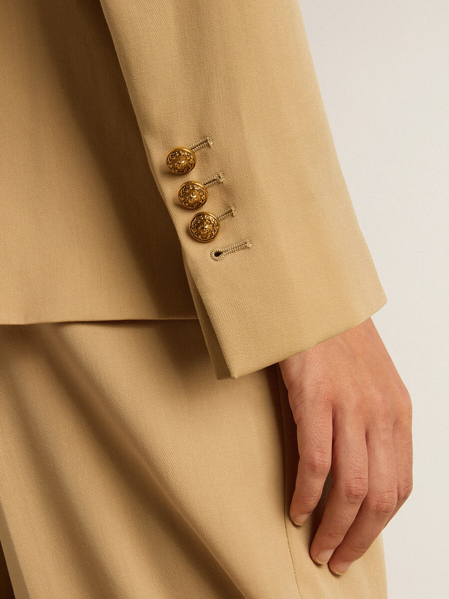 damesblazer met dubbele rij knopen in zandkleur met gouden knopen in heraldisch motief.
