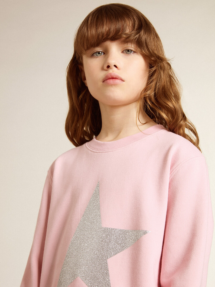 roze sweatshirt met een grote ster van zilveren glitter op de voorkant.