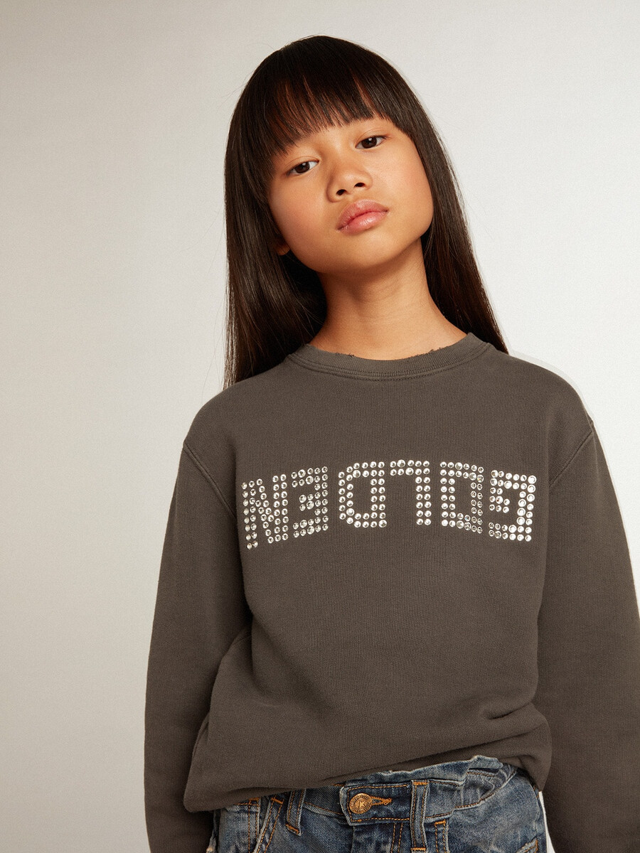 een verwassen grijze sweater met kristallen letters.