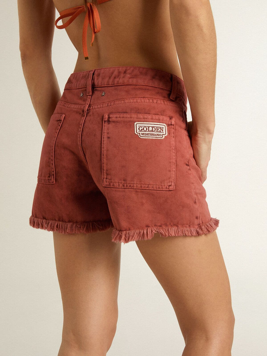 damesshorts van baksteenrood denim met golden mediterraneo-borduurwerk.