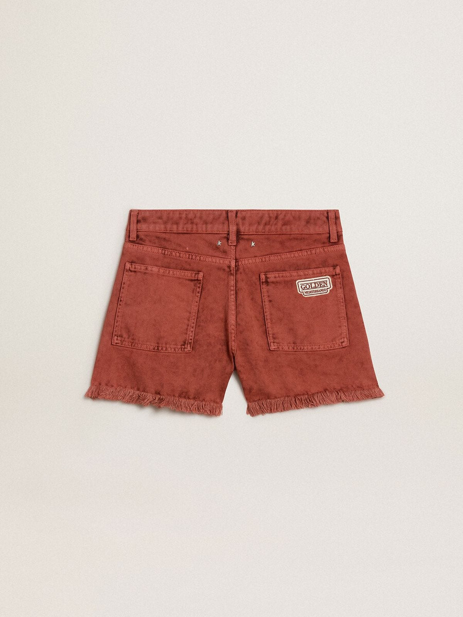 damesshorts van baksteenrood denim met golden mediterraneo-borduurwerk.