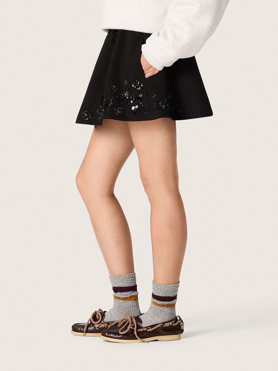 damesminirok van zwarte katoenen twill met geborduurde bloemen en pailletten.