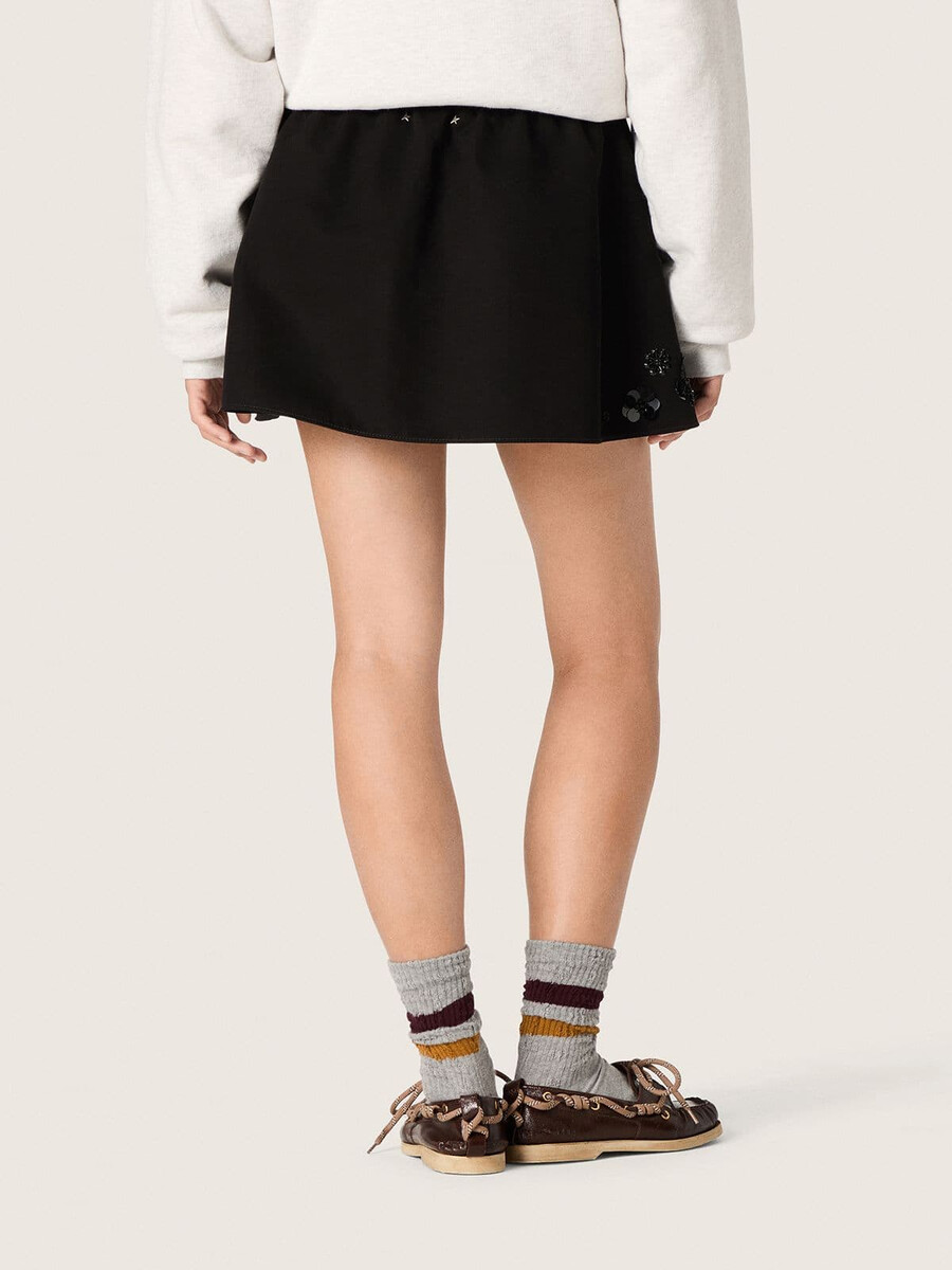 damesminirok van zwarte katoenen twill met geborduurde bloemen en pailletten.
