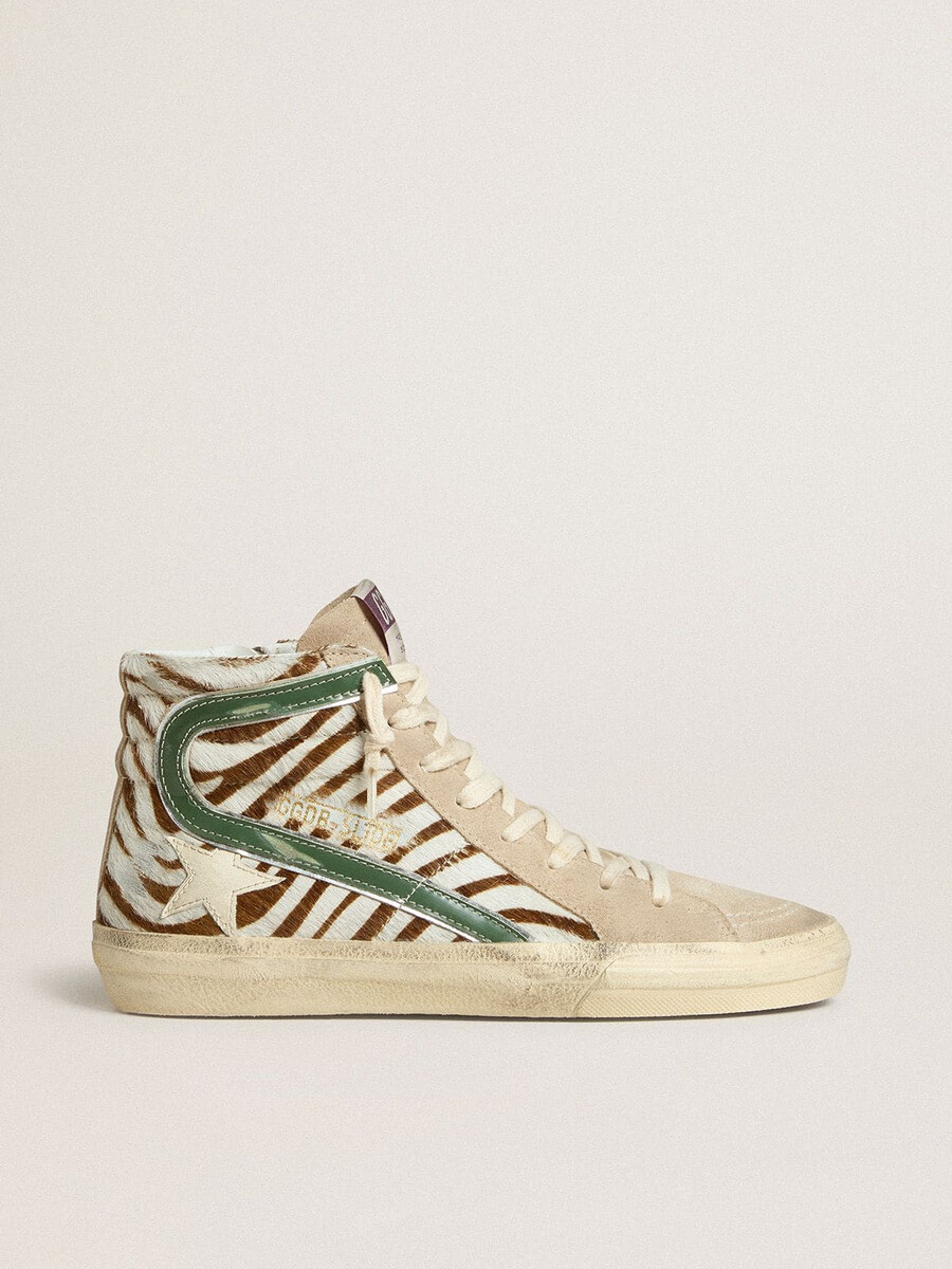 damesslippers van ponyhuid met zebraprint en groene gelamineerde leren accenten.