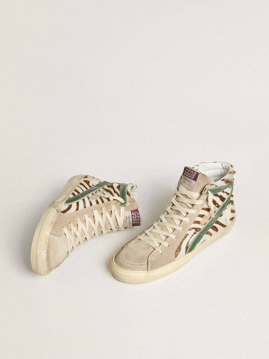 damesslippers van ponyhuid met zebraprint en groene gelamineerde leren accenten.