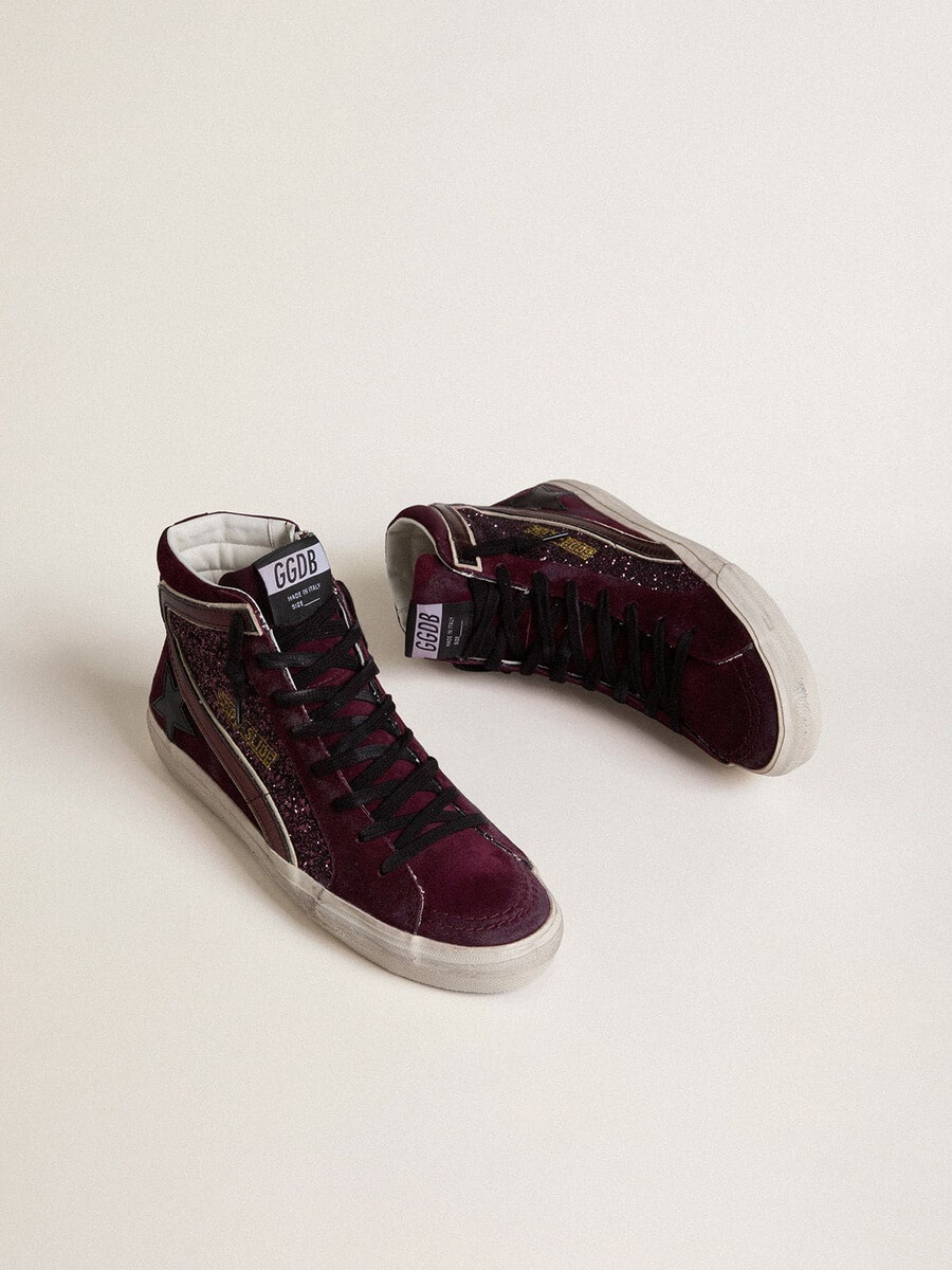 damesslippers in zwart kersenrood met glitter en suède met een leren ster en een metallic leren accent.