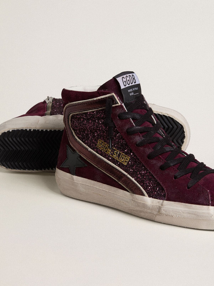 damesslippers in zwart kersenrood met glitter en suède met een leren ster en een metallic leren accent.