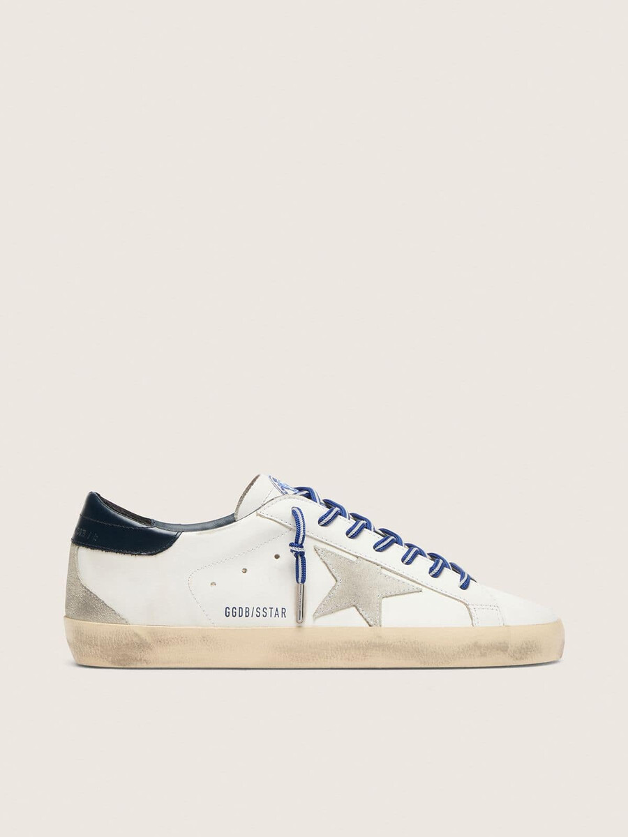 de super-star ltd herensneaker geïnspireerd op tennis is uitgevoerd in wit leer met een suède ster en een blauwe leren hielband.