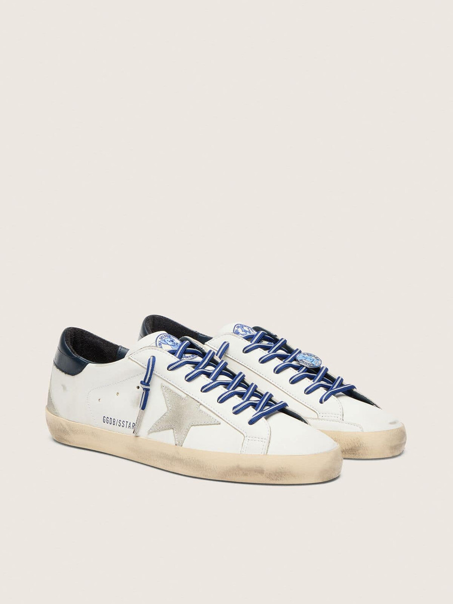 de super-star ltd herensneaker geïnspireerd op tennis is uitgevoerd in wit leer met een suède ster en een blauwe leren hielband.