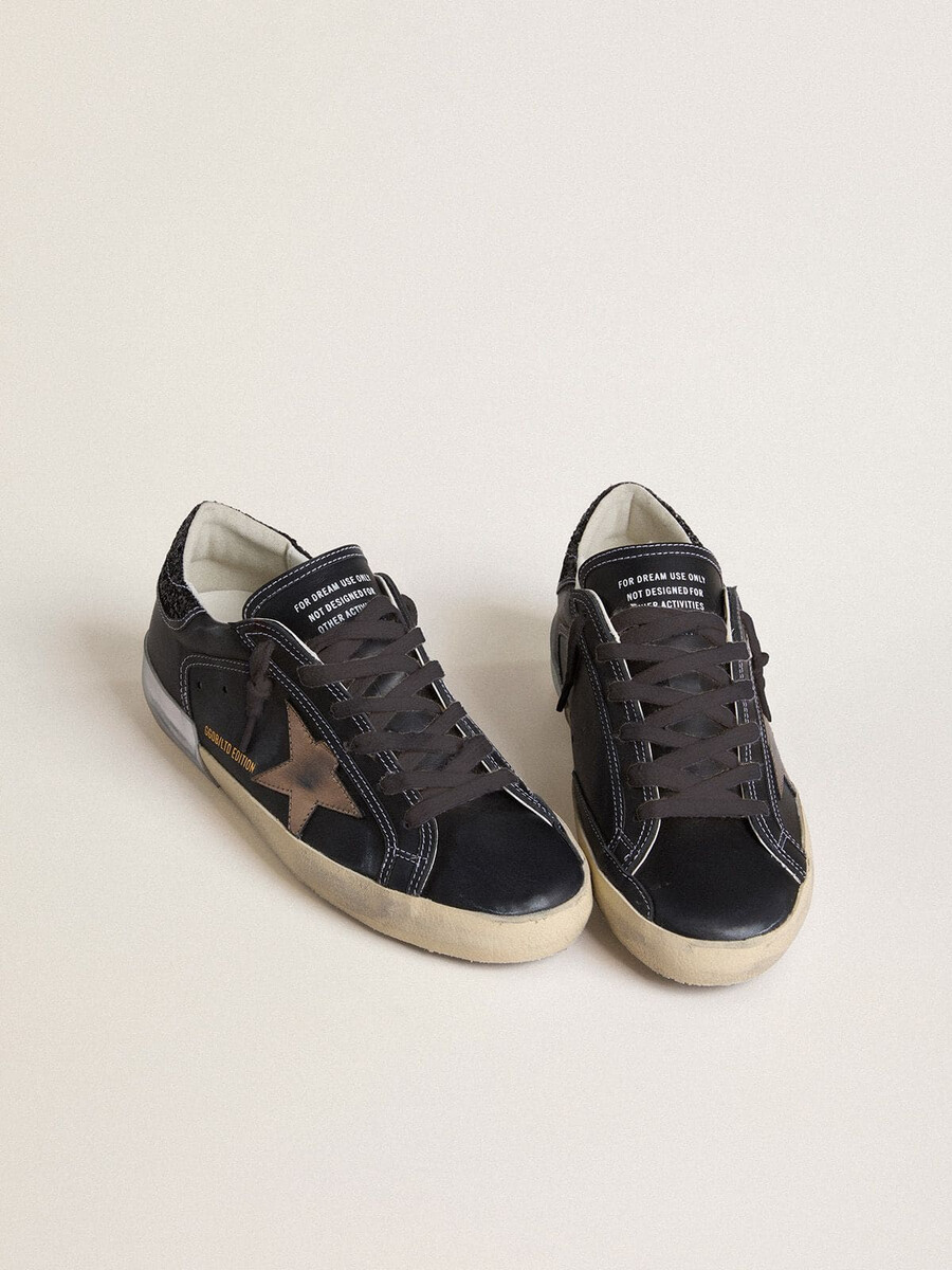 dames super-star ltd in zwart leer met gouden leren ster en zwarte glitter hielstuk.