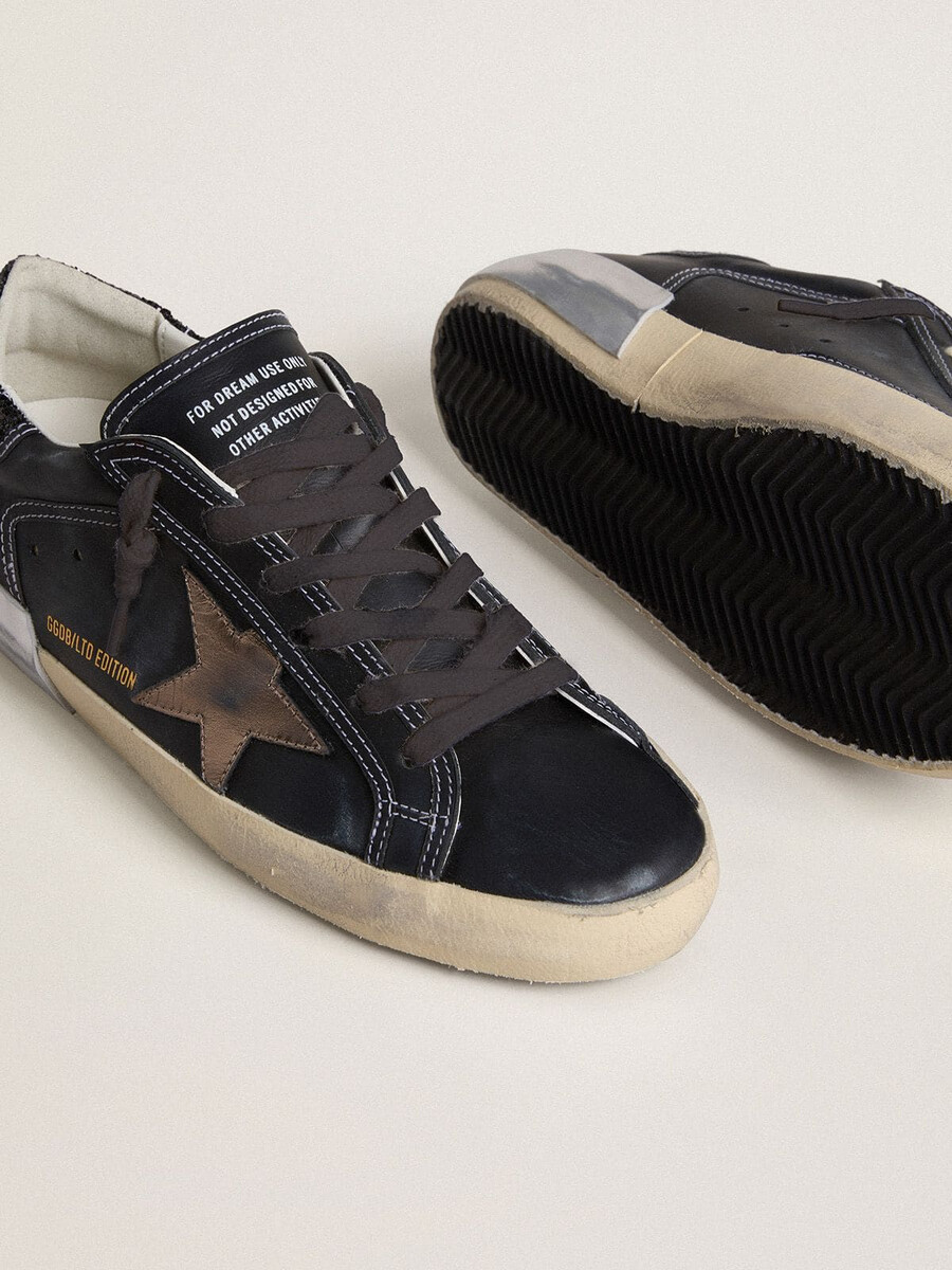 dames super-star ltd in zwart leer met gouden leren ster en zwarte glitter hielstuk.