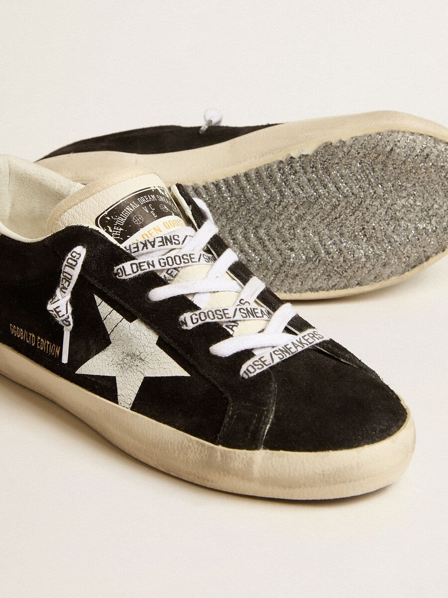 dames super-star ltd in zwart suède met witte geprinte ster en zilverkleurige glitter op de hiel.