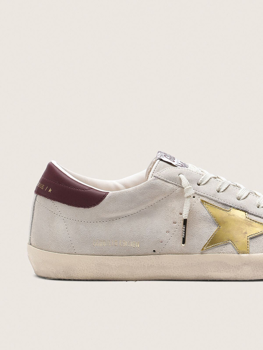 dames super-star cny in ivoorkleurig suède met metallic leren ster en leren hielstuk.