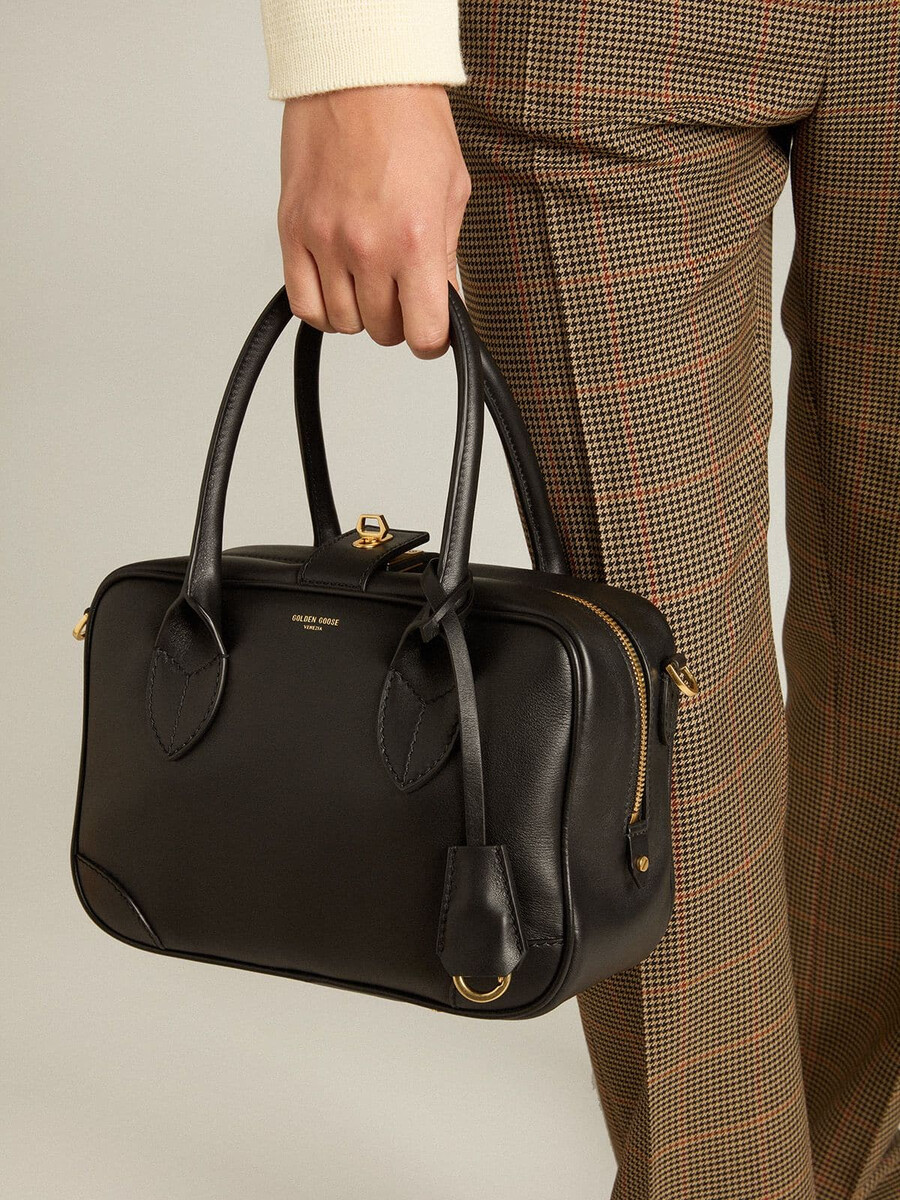vita-tas van glad zwart leer met gouden details.