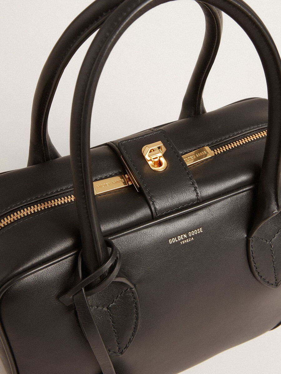 vita-tas van glad zwart leer met gouden details.