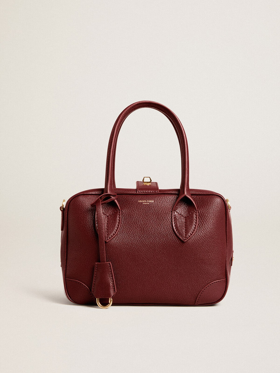 vita-tas van bordeauxrood leer met gouden details.