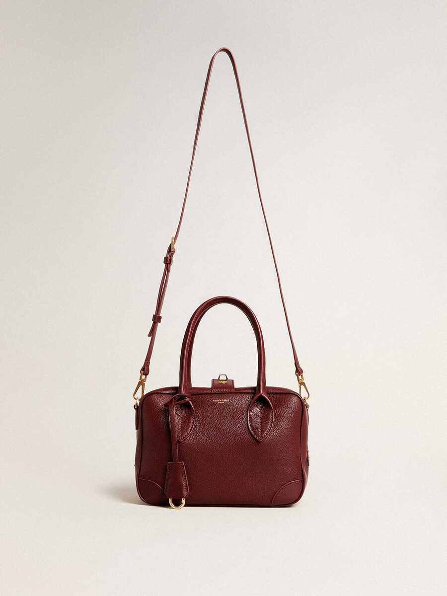 vita-tas van bordeauxrood leer met gouden details.