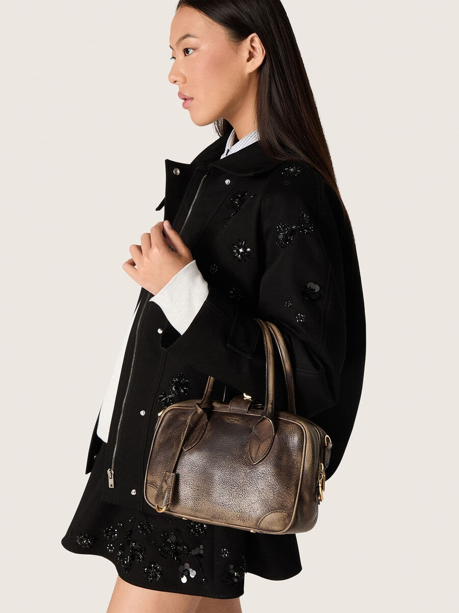 vita-tas van bruin vintage leer met gouden details.