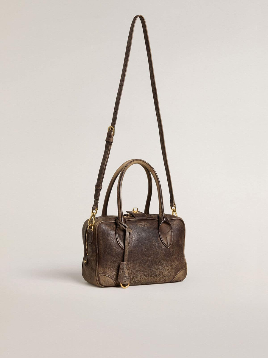 vita-tas van bruin vintage leer met gouden details.