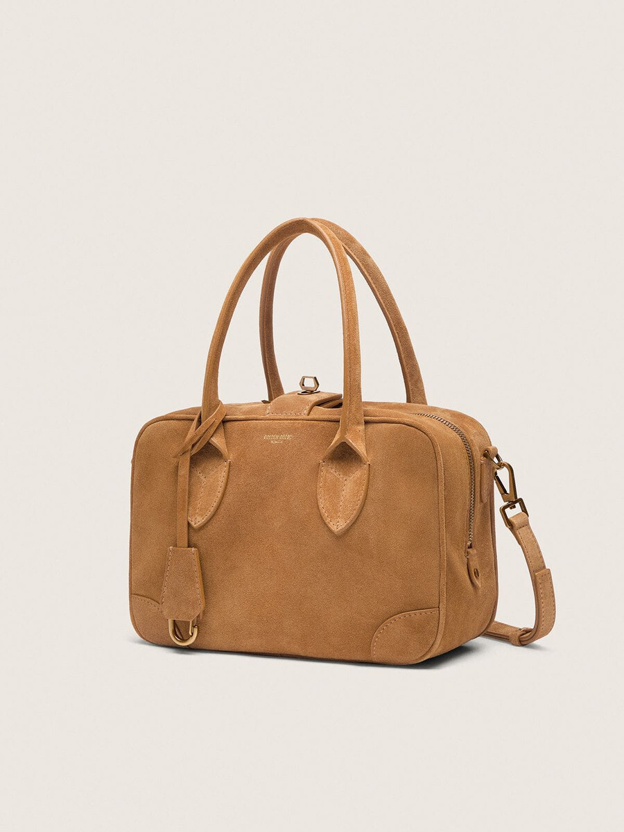 vita-tas van camelkleurig suède met gouden details.