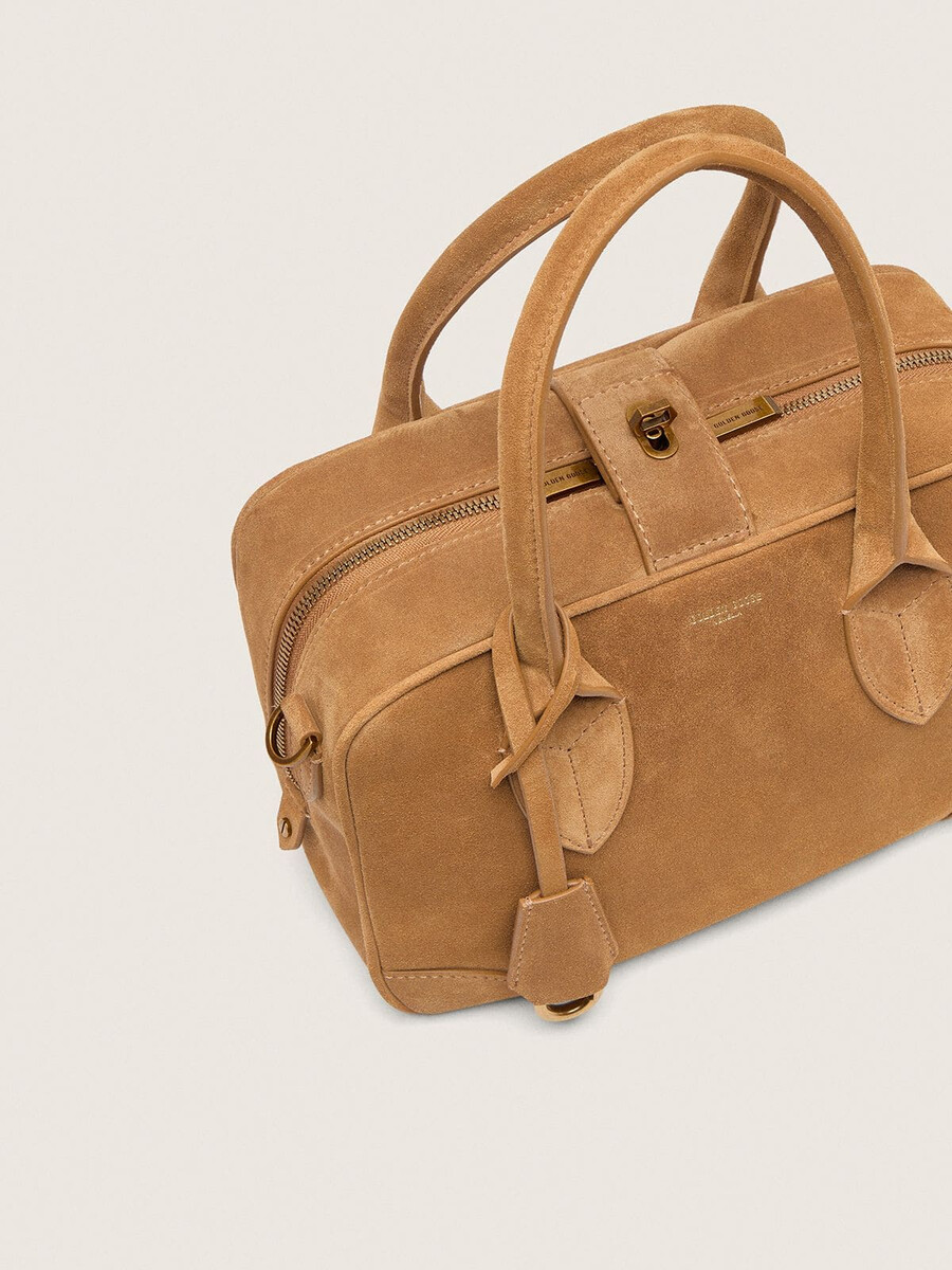 vita-tas van camelkleurig suède met gouden details.